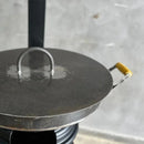Chapa de ferro com tampa redonda e alça amarela para fogão a lenha