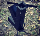 Fogão portátil de metal preto para camping ao ar livre, sobre grama com folhas secas