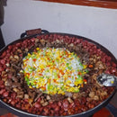 Panela grande com linguiça, carnes variadas e legumes picados coloridos no centro