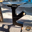 Churrasqueira de chapa metálica com suporte para lenha em ambiente externo, com alças de madeira