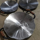 Três chapas de disco de arado metálicas com cabos de madeira sobre chão de concreto